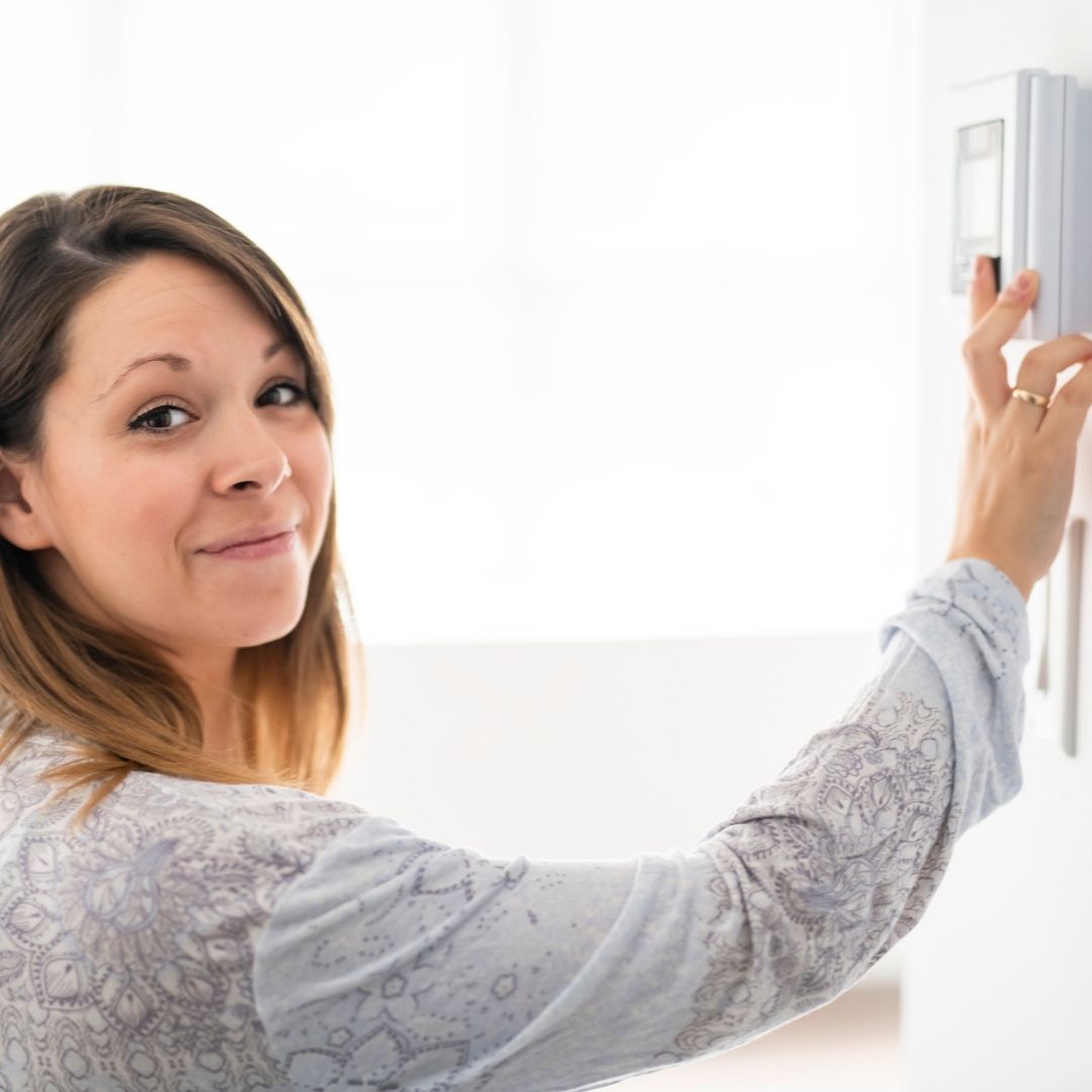 woman adjusting thermostat
